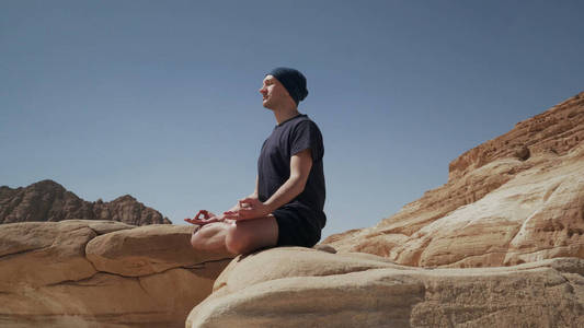 沙漠中一个英俊的男人坐在石头上莲花的姿势