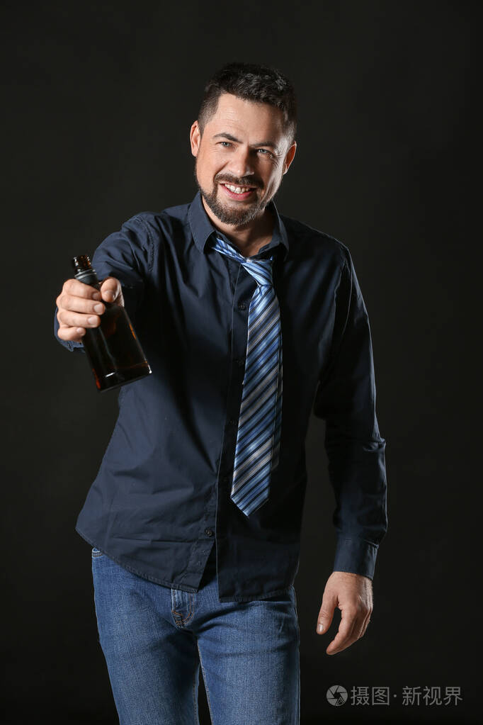 在黑暗背景下喝酒的成熟男人