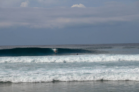 在阳光明媚的大自然中，欢快的冲浪者骑着巨大的泡沫海浪。米
