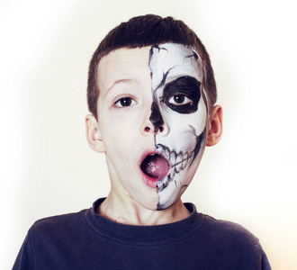 人们万圣节可爱的小男孩用脸漆似的骷髅来庆祝万圣节,人们的生活方式