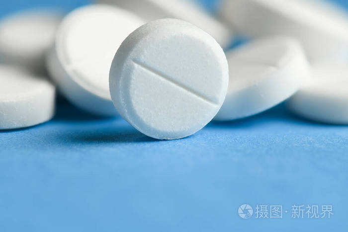 蓝色背景的白色药丸宏观照片概念药物和药物治疗保健