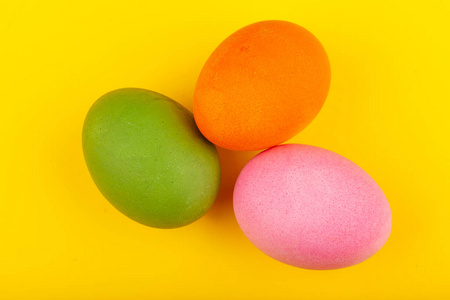 彩色手工复活节彩蛋。三个鸡蛋的俯视图。被隔离在黄色背景上。准备复活节。