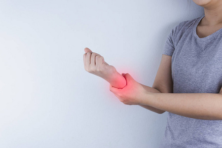 Closeup woman holds her wrist pain on white background with red 