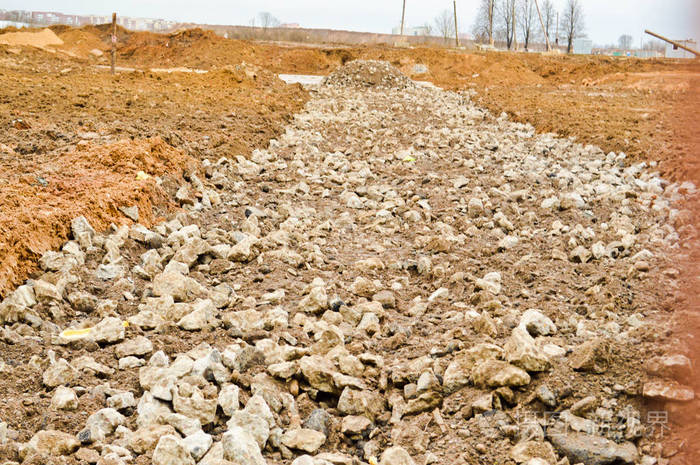 一条脏兮兮的坏土路泥泞路面上有水坑和粘土干泥有裂缝和车辙越野背景