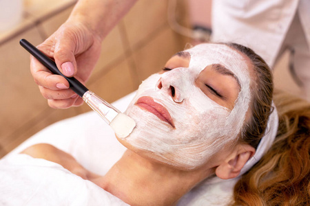 Cosmetician applying a facial layer beauty mask 