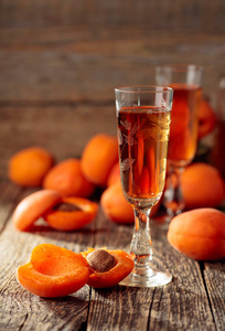 Apricot liquor and fresh apricots on a wooden table. 