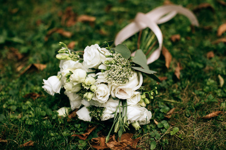 一束白玫瑰在绿草上。婚礼装饰和配件