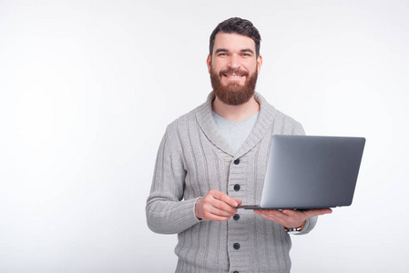 Handsome guy is holding his laptop and smiling 