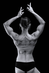 强壮的女人，肌肉发达的身体在黑色背景下摆姿势