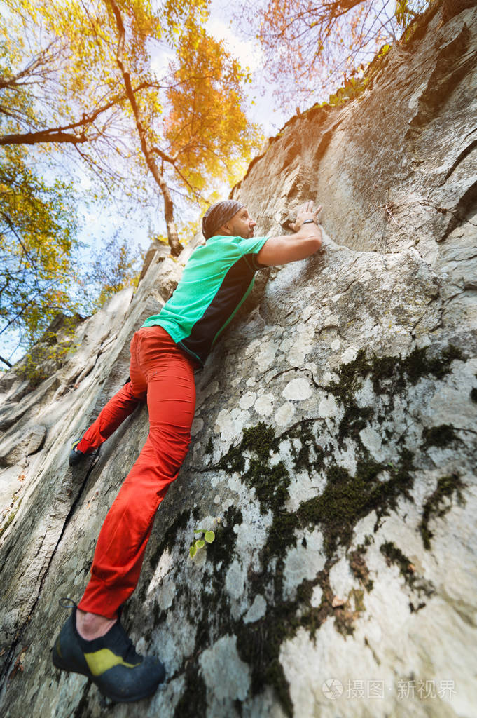 一个自由的老年男性登山者挂在山林中的岩壁上成熟的体育理念