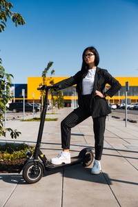 坐在停车场电动滑板车上的商务女性无排放环保交通工具