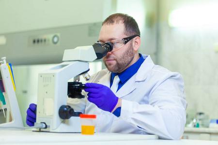在医学实验室使用显微镜和实验室设备进行尿液分析的实验室工作者