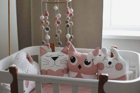 Beautiful interior of baby room with a crib. White crib with pil