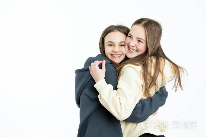 在蓝色背景下欣喜若狂的朋友们拥抱在一起摄影棚拍摄的欢快的女孩看着