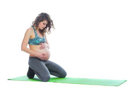 美丽孕妇训练。在怀孕的最后几个月做健身运动。瑜伽姿势。做母亲，怀孕，瑜伽概念。孤立的白色背景。