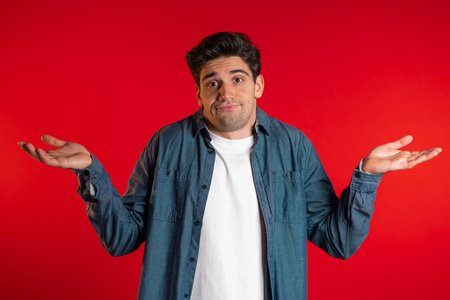 穿着牛仔衬衫的年轻帅气的小伙子耸耸肩,做了个不知道的手势,无可奈何