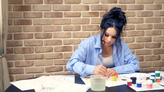 美丽的黑发女孩用水粉画。创意工作室