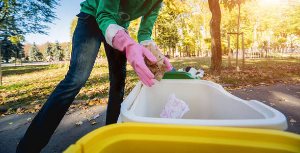 Volunteer girl sorts garbage in the street of the park. Concept 