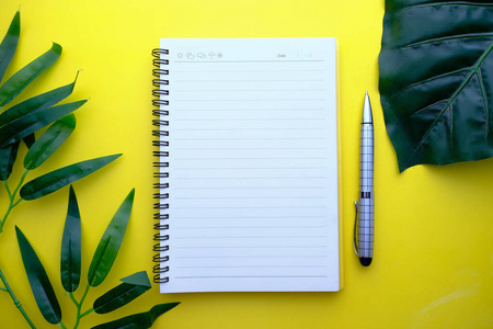 top view of open notepad and pen on yellow background 