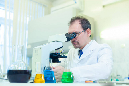 化学家疯了。一个疯狂的科学家在科学实验室里做实验。用显微镜进行研究。