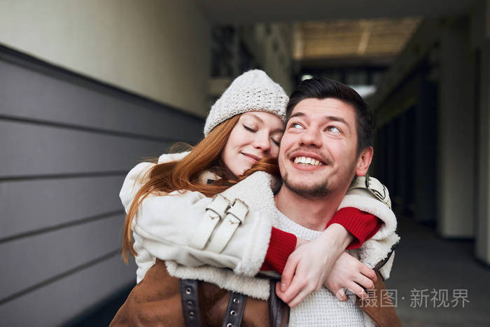 戴着白帽子和外套的年轻漂亮女人拥抱着她的男朋友