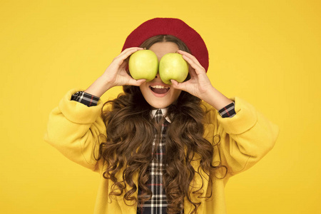 小孩拿水果吃苹果有助于学习.小孩拿着黄色背景的苹果.