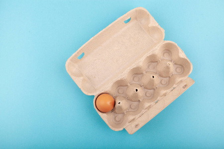 鸡蛋鸡蛋。一个打开的灰色盒子的俯视图，棕色的鸡蛋被隔离在蓝色的背景上。健康生活方式的概念，获取纯蛋白质。适当的早餐。一个鸡蛋。