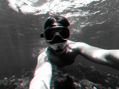 一名潜水员戴着潜水面罩在水下碧绿的海水中游泳自拍