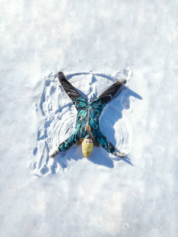 快乐的女孩躺在雪地上画出雪天使的身影