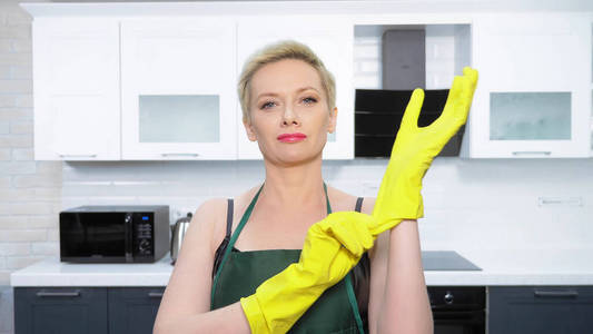  humor. woman in leather corset, puts on rubber gloves. cleaning