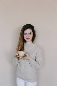 A girl drinking coffee in the kitchen at home. Young woman holdi