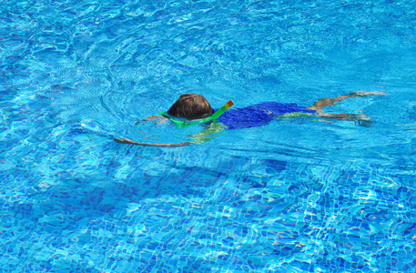 室外游泳池里的儿童水下眼镜。这孩子在游泳池里学游泳。