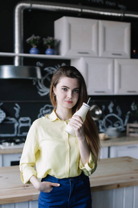 A girl drinking coffee in the kitchen at home. Young woman holdi