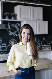 A girl drinking coffee in the kitchen at home. Young woman holdi