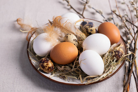 圣诞彩蛋放在桌上柳枝做成的粘土盘子里。浅背景复活节快乐概念。平面布置图