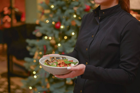 餐厅里的女服务员端着菜,端着蔬菜沙拉.照片