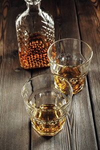 旧木桌上的威士忌酒杯和酒瓶