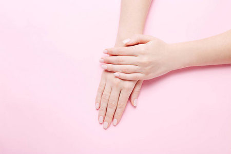 粉红色背景上有漂亮指甲的女士手。手部spa概念