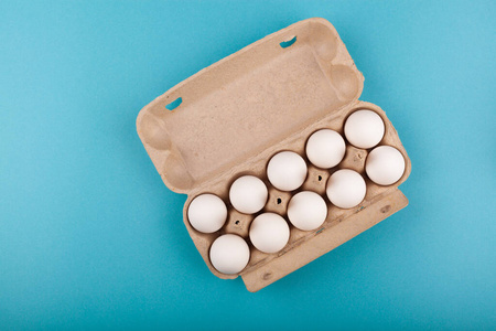 鸡蛋鸡蛋。打开的灰色盒子和白色鸡蛋的俯视图。被隔离在蓝色背景下。健康生活方式的概念，获取纯蛋白质。适当的早餐。十个鸡蛋。