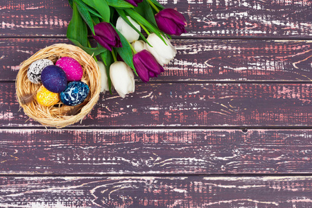 复活节彩蛋和郁金香放在木板上。创意照片。