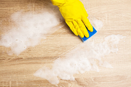 Employee using sponge for cleaning wood table