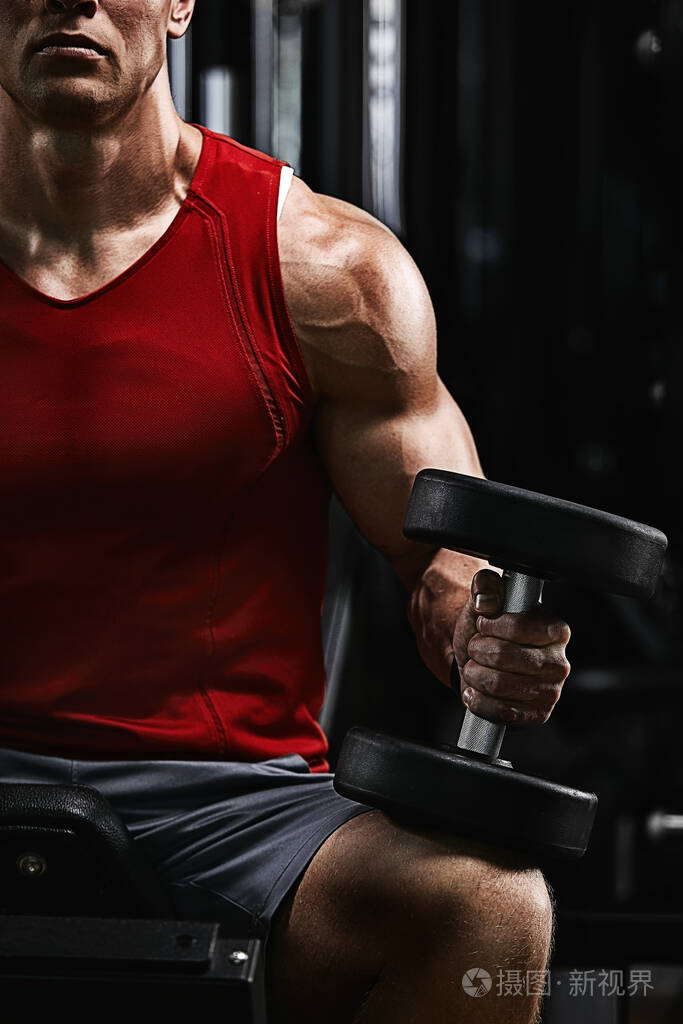 年轻体育运动员健身模特,在体育馆里摇动二头肌哑铃写真.