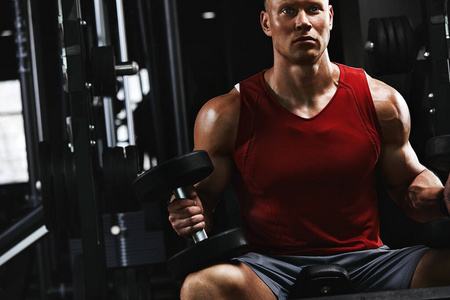 年轻体育运动员健身模特,在体育馆里摇动二头肌哑铃写真.