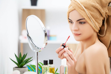 准备上班的女人在家里对着浴室的镜子化妆。