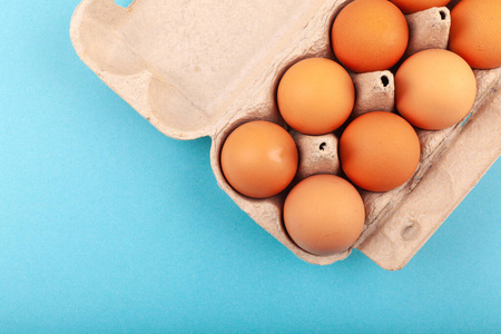 鸡蛋鸡蛋。一个打开的灰色盒子的俯视图，棕色的鸡蛋被隔离在蓝色的背景上。健康生活方式的概念，获取纯蛋白质。适当的早餐。迪萨帝鸡蛋。