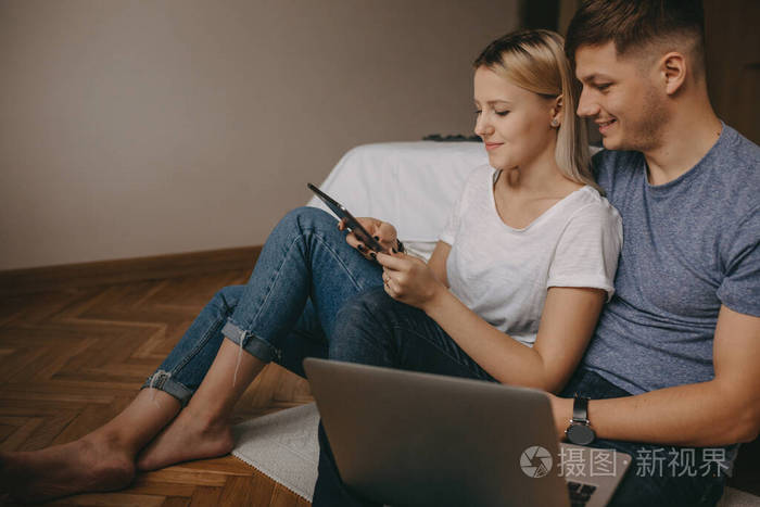 高加索夫妇坐在地板上用现代科技享受美好时光