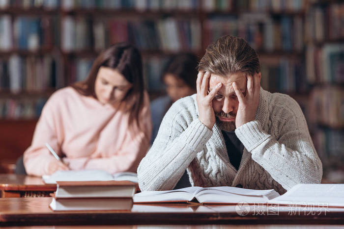 有胡子的男人在图书馆看书时看起来很累