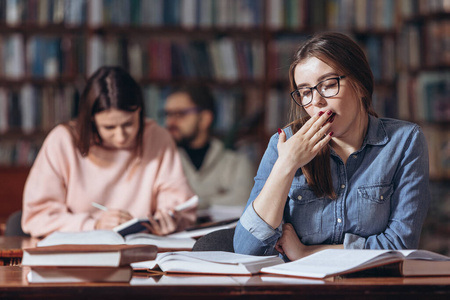 年轻学生在大学图书馆感到疲倦