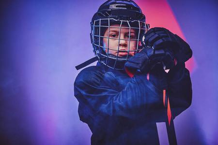 年轻认真的曲棍球运动员穿着制服在霓虹灯下拍照