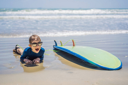 年轻的冲浪者，快乐的小男孩在沙滩上冲浪